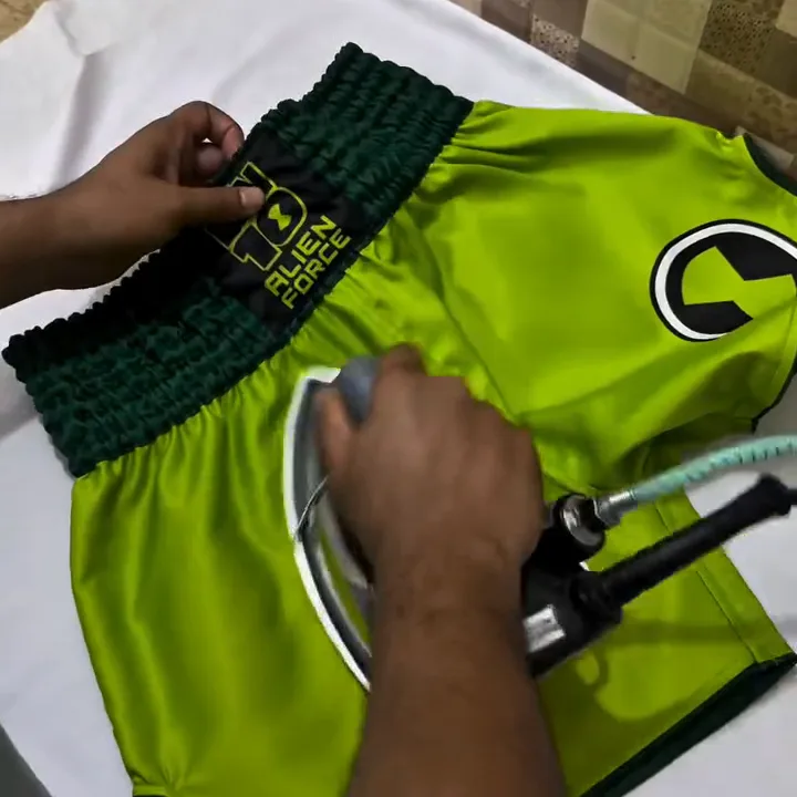 Custom Muay Thai shorts being pressed and finished at the FJ Sportswear factory in Sialkot