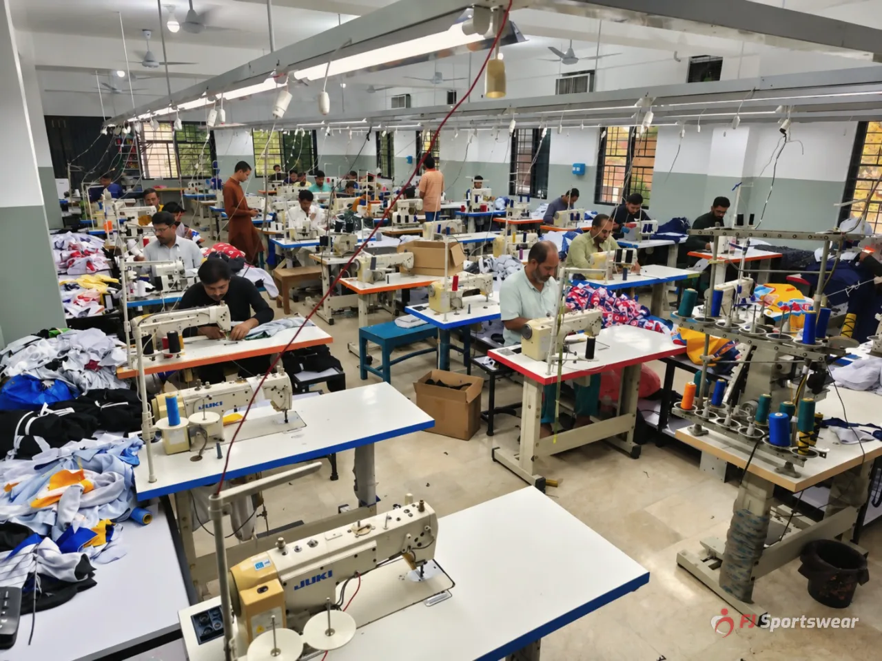 Sewing and stitching floor with rows of industrial sewing machines making custom team uniforms