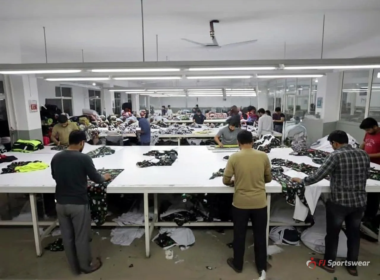 Workers cutting and sorting sublimated sportswear panels on large tables