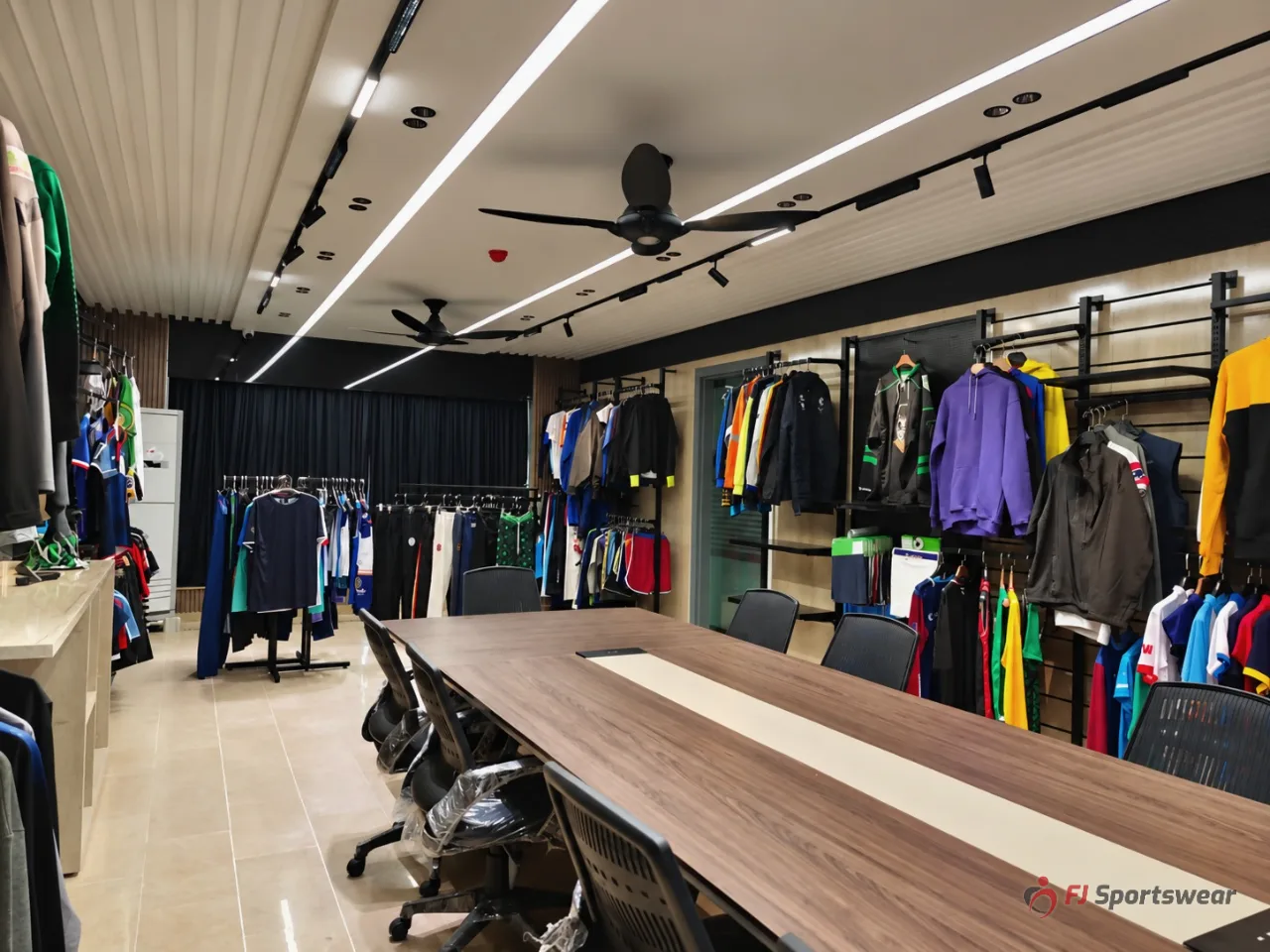 FJ Sportswear sample showroom with team uniforms, hoodies, jackets and a client meeting table